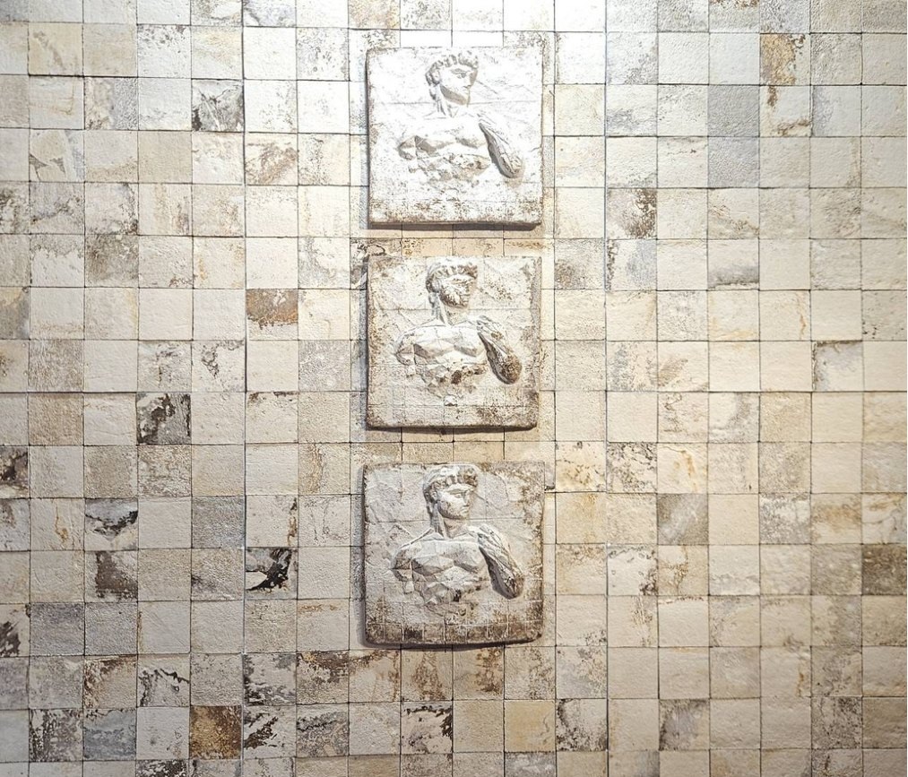 A MUSH decorative composition combining small patterned panels and three relief portraits